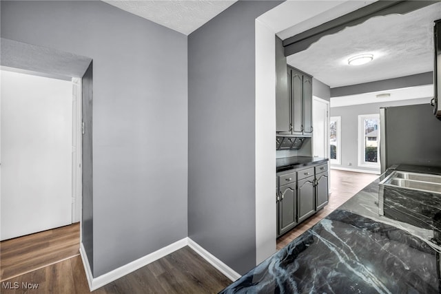kitchen featuring baseboards, dark countertops, dark wood-type flooring, and a textured ceiling