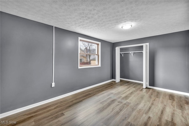 unfurnished bedroom with baseboards, a closet, wood finished floors, and a textured ceiling