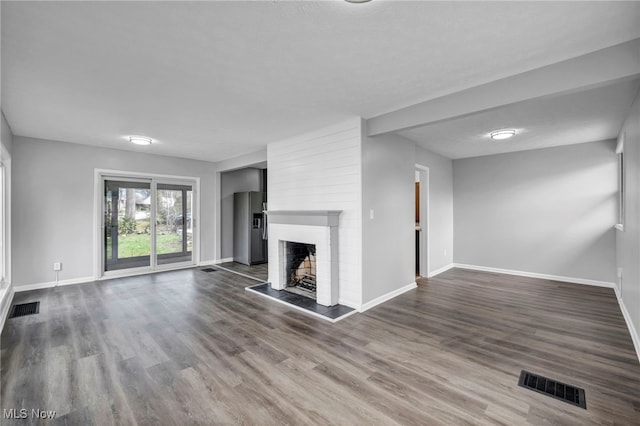 unfurnished living room with a fireplace, visible vents, and dark wood finished floors