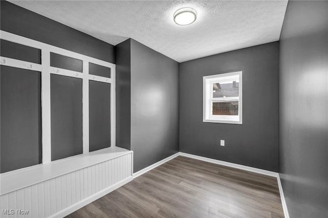 spare room with baseboards, wood finished floors, and a textured ceiling