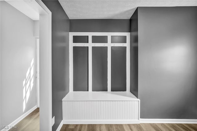 mudroom with baseboards, a textured ceiling, and wood finished floors