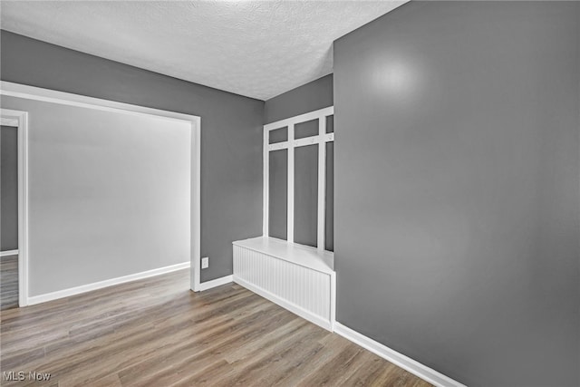 unfurnished bedroom featuring baseboards, wood finished floors, and a textured ceiling