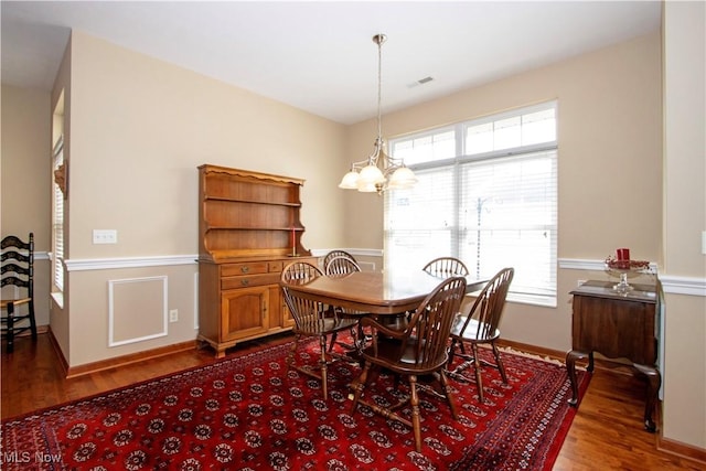 dining room with dark wood-style flooring, a wealth of natural light, visible vents, and an inviting chandelier