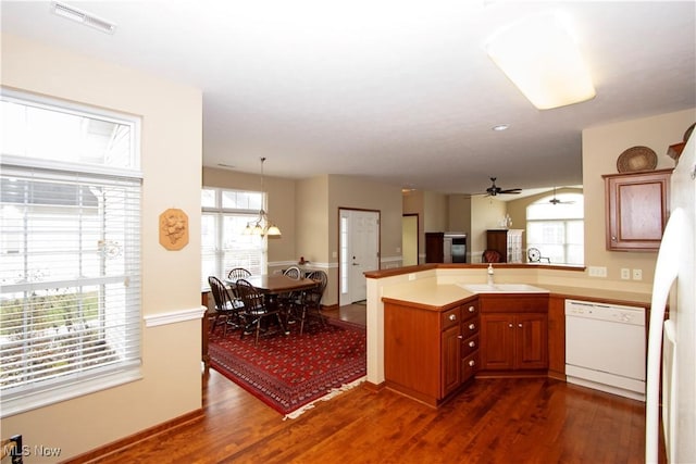 kitchen with white appliances, dark wood finished floors, visible vents, a peninsula, and brown cabinets
