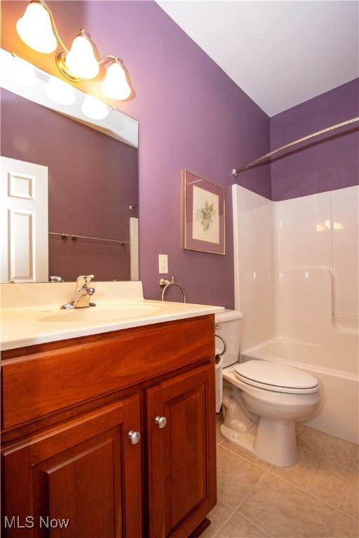 full bath with shower / tub combination, toilet, vanity, and tile patterned floors