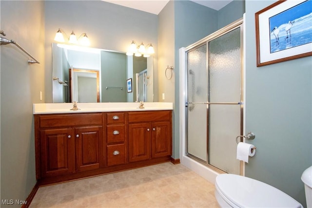 full bath featuring double vanity, a sink, a stall shower, and toilet
