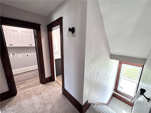 hallway featuring light carpet and baseboards