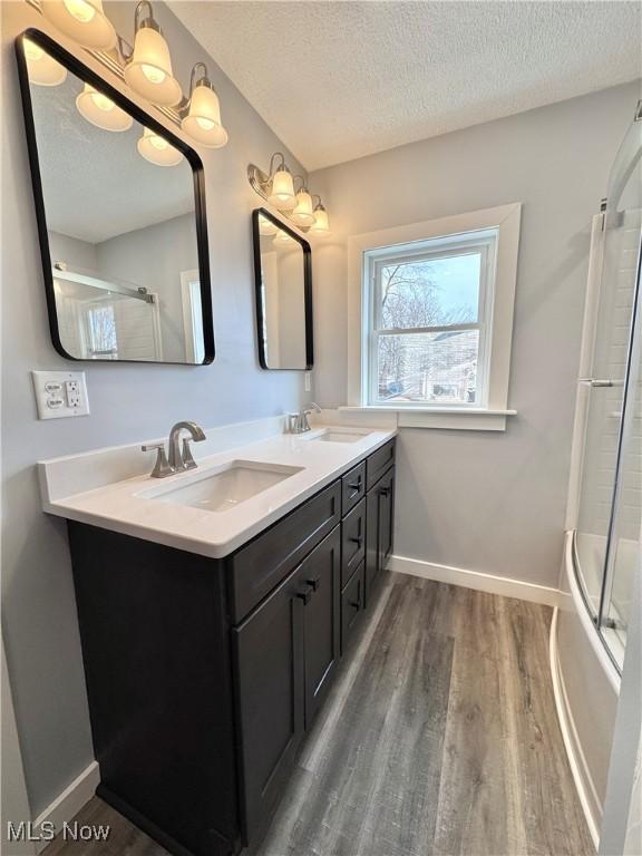 bathroom featuring double vanity, wood finished floors, a sink, and a textured ceiling