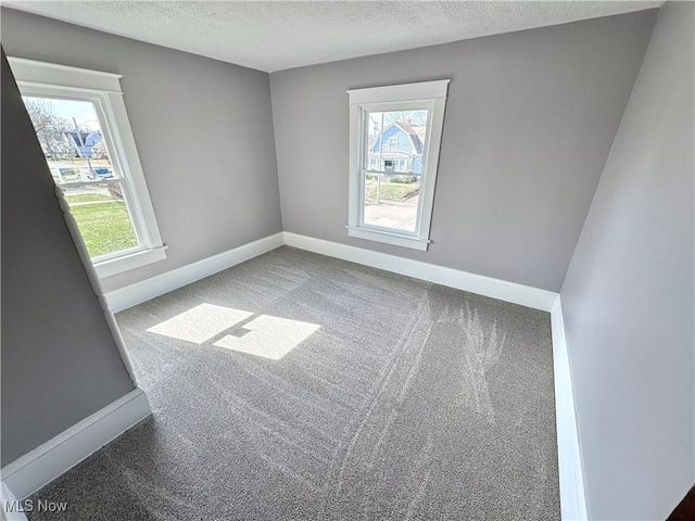 carpeted spare room with baseboards and a textured ceiling