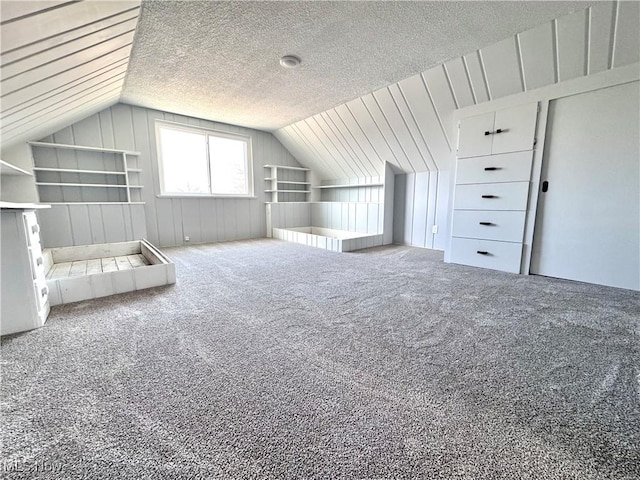 bonus room featuring carpet, vaulted ceiling, and a textured ceiling