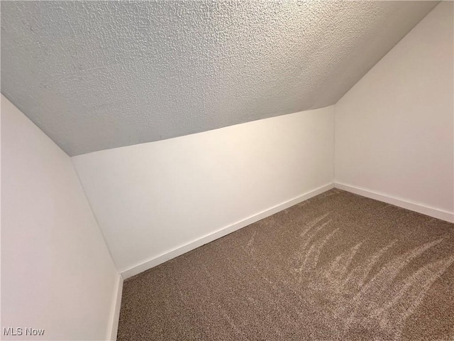 bonus room with baseboards, vaulted ceiling, carpet, and a textured ceiling