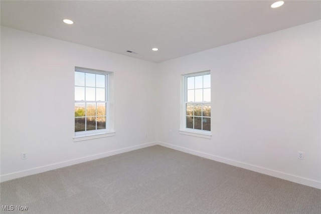 carpeted empty room with baseboards, visible vents, and recessed lighting