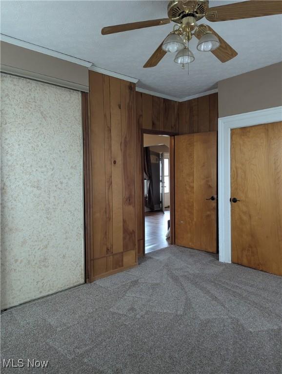 11154 Edgerton Rd, North Royalton, OH 44133 - unfurnished bedroom featuring carpet floors, crown molding, multiple closets, ceiling fan, and wood walls