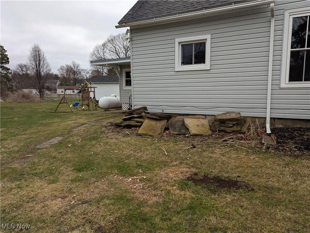 11154 Edgerton Rd, North Royalton, OH 44133 - view of side of property with a shingled roof, a lawn, and a playground