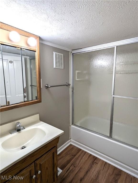 11154 Edgerton Rd, North Royalton, OH 44133 - full bathroom with wood finished floors, vanity, shower / bath combination with glass door, and a textured ceiling