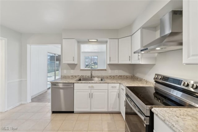 kitchen featuring a sink, white cabinetry, light tile patterned floors, wall chimney range hood, and stainless steel appliances
