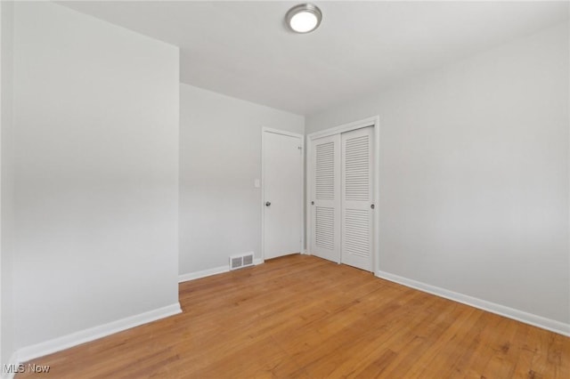 spare room featuring baseboards, light wood finished floors, and visible vents