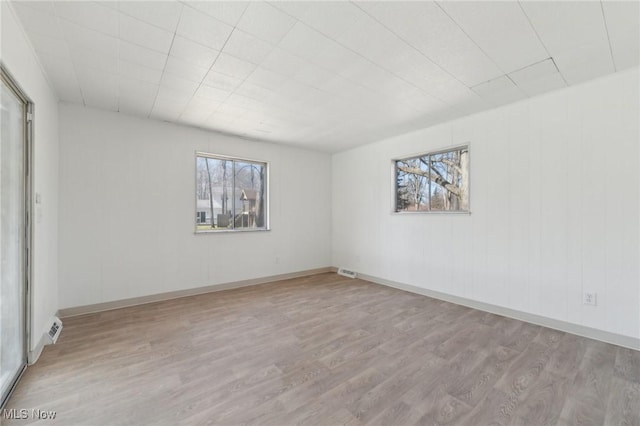 unfurnished room with visible vents, wood finished floors, and plenty of natural light
