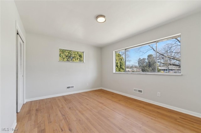 unfurnished bedroom featuring light wood-type flooring, a closet, baseboards, and visible vents