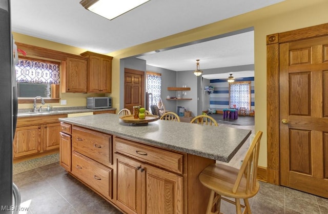 kitchen featuring a sink, a wealth of natural light, stainless steel microwave, and a breakfast bar