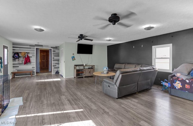 living room with a ceiling fan, a textured ceiling, and wood finished floors