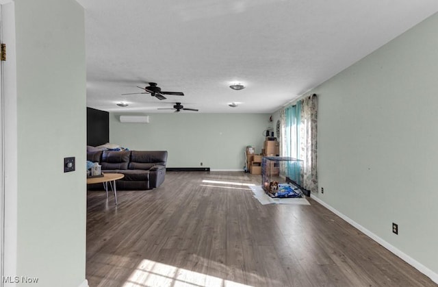 living room featuring an AC wall unit, baseboards, a textured ceiling, a ceiling fan, and wood finished floors