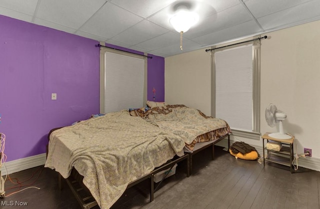 bedroom featuring baseboards, a paneled ceiling, and hardwood / wood-style floors