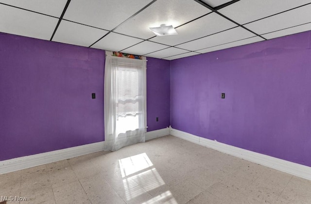 empty room with baseboards, tile patterned floors, and a paneled ceiling