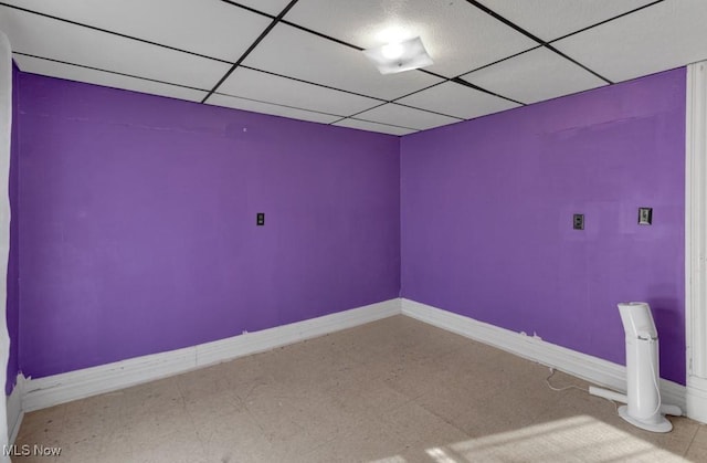 empty room with baseboards, tile patterned floors, and a paneled ceiling