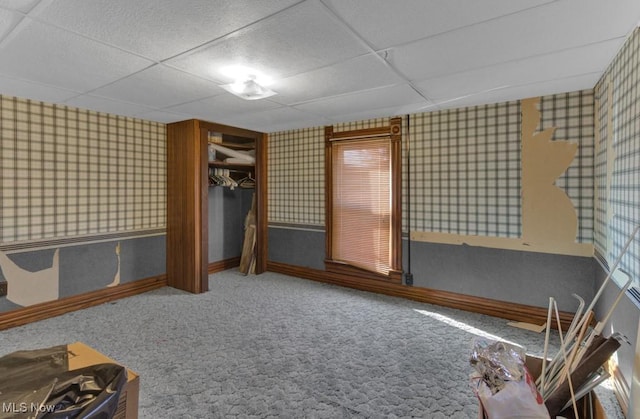 unfurnished bedroom featuring carpet flooring, wallpapered walls, and a paneled ceiling
