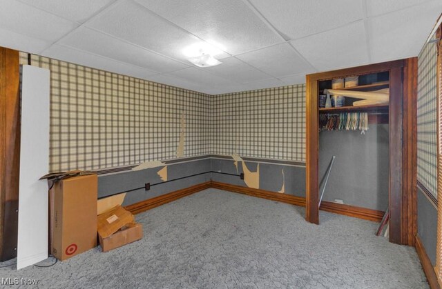 interior space with wallpapered walls, carpet floors, a closet, and a paneled ceiling