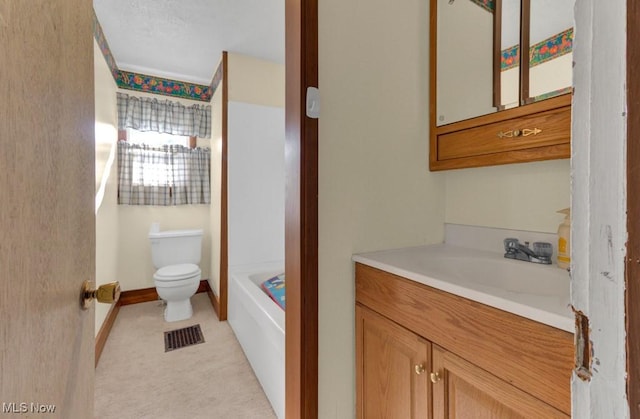 bathroom featuring a bathing tub, toilet, vanity, baseboards, and visible vents