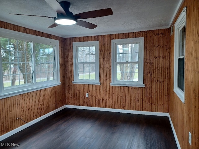 unfurnished room with a ceiling fan, a textured ceiling, baseboards, and dark wood finished floors
