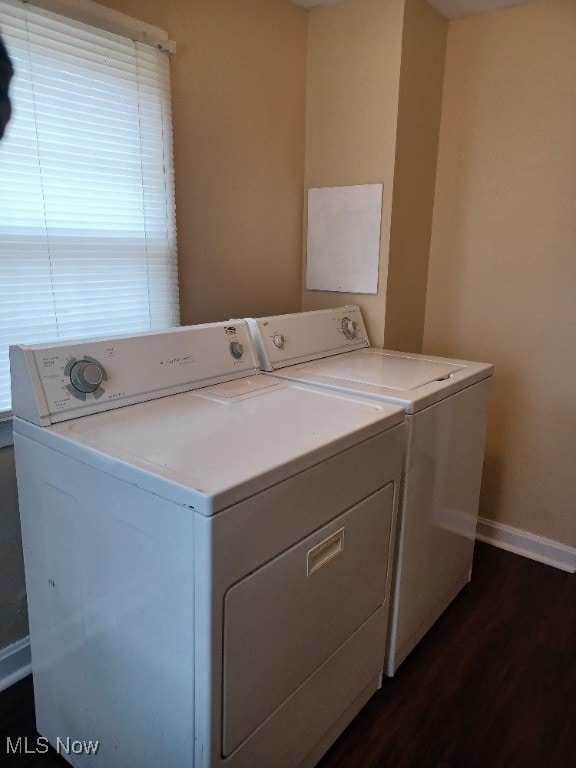 clothes washing area with washing machine and dryer, baseboards, laundry area, and dark wood finished floors