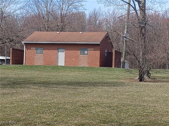 view of property exterior with brick siding and a lawn