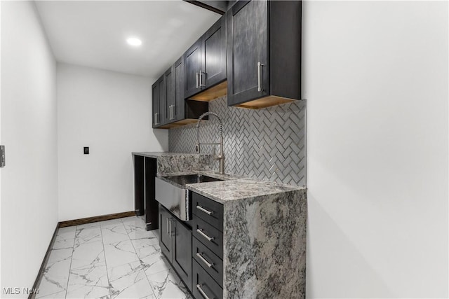 3189 Chardonnay Ln, Poland, OH 44514 - kitchen with baseboards, light stone counters, decorative backsplash, marble finish floor, and a sink