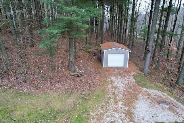 view of yard featuring driveway, a detached garage, and an outbuilding