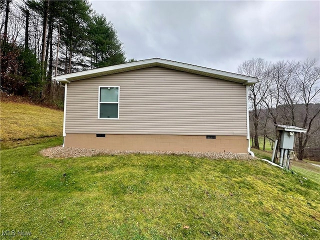 view of side of home with crawl space and a yard