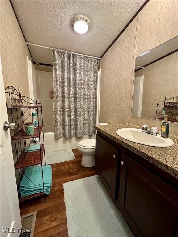 bathroom featuring toilet, wood finished floors, a textured ceiling, shower / bath combo with shower curtain, and a textured wall