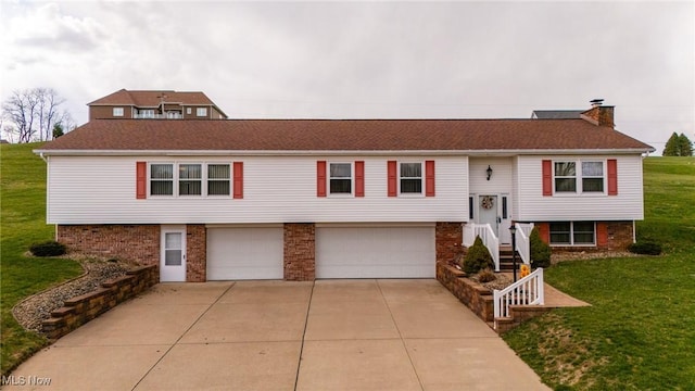 bi-level home with a chimney, concrete driveway, a front lawn, and an attached garage
