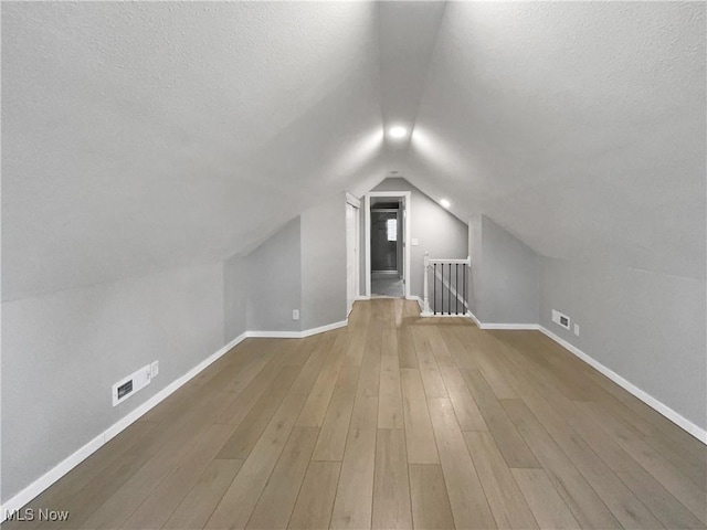 8414 York Rd, North Royalton, OH 44133 - additional living space with vaulted ceiling, visible vents, wood finished floors, baseboards, and a textured ceiling
