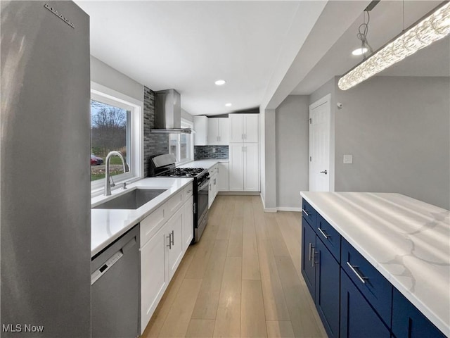 8414 York Rd, North Royalton, OH 44133 - kitchen with range with gas cooktop, stainless steel dishwasher, a sink, wall chimney exhaust hood, and blue cabinetry