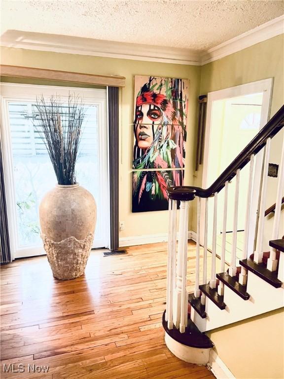1655 Ivydale Rd, Cleveland Heights, OH 44118 - stairs featuring ornamental molding, baseboards, a textured ceiling, hardwood / wood-style flooring, and visible vents