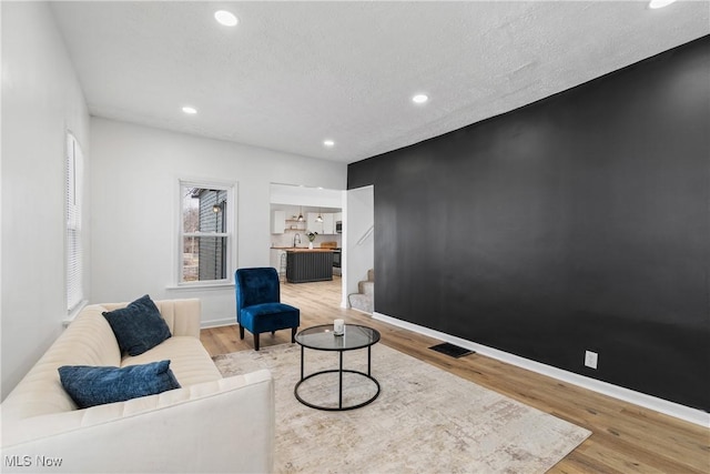 living area featuring baseboards, stairway, light wood-style flooring, and recessed lighting