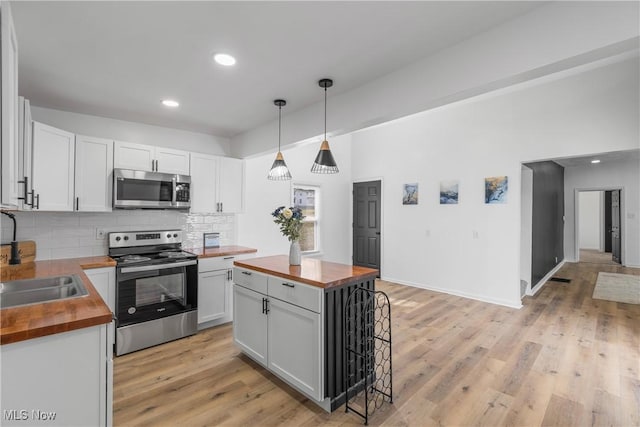 kitchen featuring stainless steel appliances, backsplash, a sink, butcher block counters, and light wood-style flooring