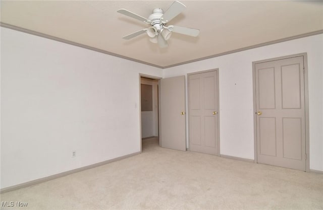 unfurnished bedroom with ornamental molding, baseboards, light colored carpet, and ceiling fan