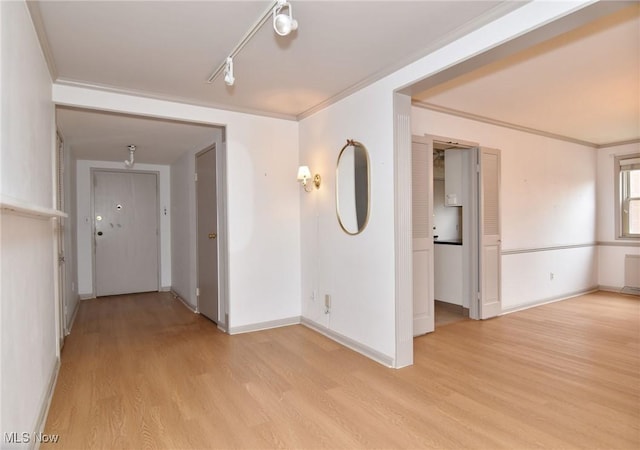 hall with rail lighting, crown molding, light wood-style floors, and baseboards