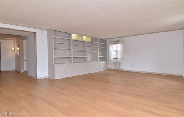 spare room with baseboards, light wood-style floors, and an inviting chandelier