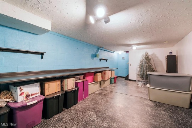 miscellaneous room featuring a textured ceiling and concrete block wall