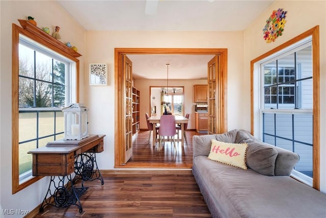 living room with baseboards, a notable chandelier, and dark wood-style flooring
